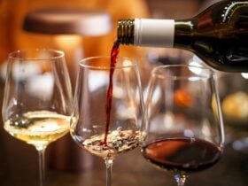 Red wine being poured from a bottle into a glass, with two other glasses pictured