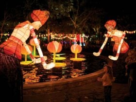 a little girl walking in front of lanterns