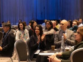 A multicultural audience clapping in recognition of the speaker.