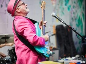 Man in pink suit is playing a guitar