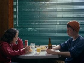A child and adult sit across from each other at a restaurant booth.