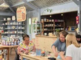 People sitting at a table painting pottery in a pottery studio