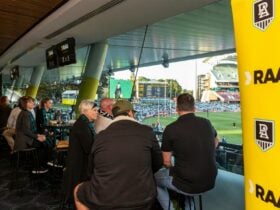People sitting on stools looking out to a football oval