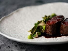 A white plate holds venison cooked rare