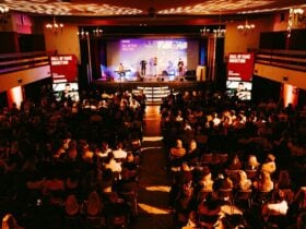 Large audience seated in a hall watching musicians performing.