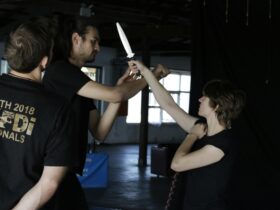 two performers participating in a choreographed knife fight for theatre, under instruction