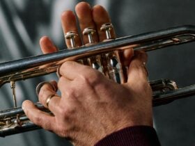 A close up photo of hands playing notes on a trumpet.