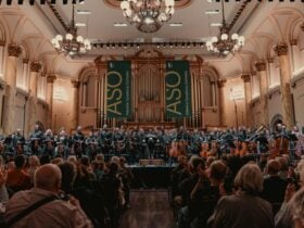 Adelaide Town Hall, with musicians bowing on stage, and audience clapping.