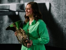 A photo of a horn player holding her instrument and smiling