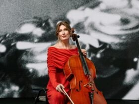 A cellist with their instrument, smiling.