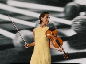 A photo of a violinist holding her instrument, smiling.