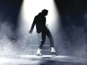 A dark silhouette of a performer in a fedora and sparkling socks, striking an iconic dance