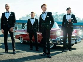 Men in suits in front of red classic car