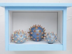 3 round clay artworks in a small white and Blue Box