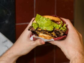 Two hands hold a juicy double beef burger
