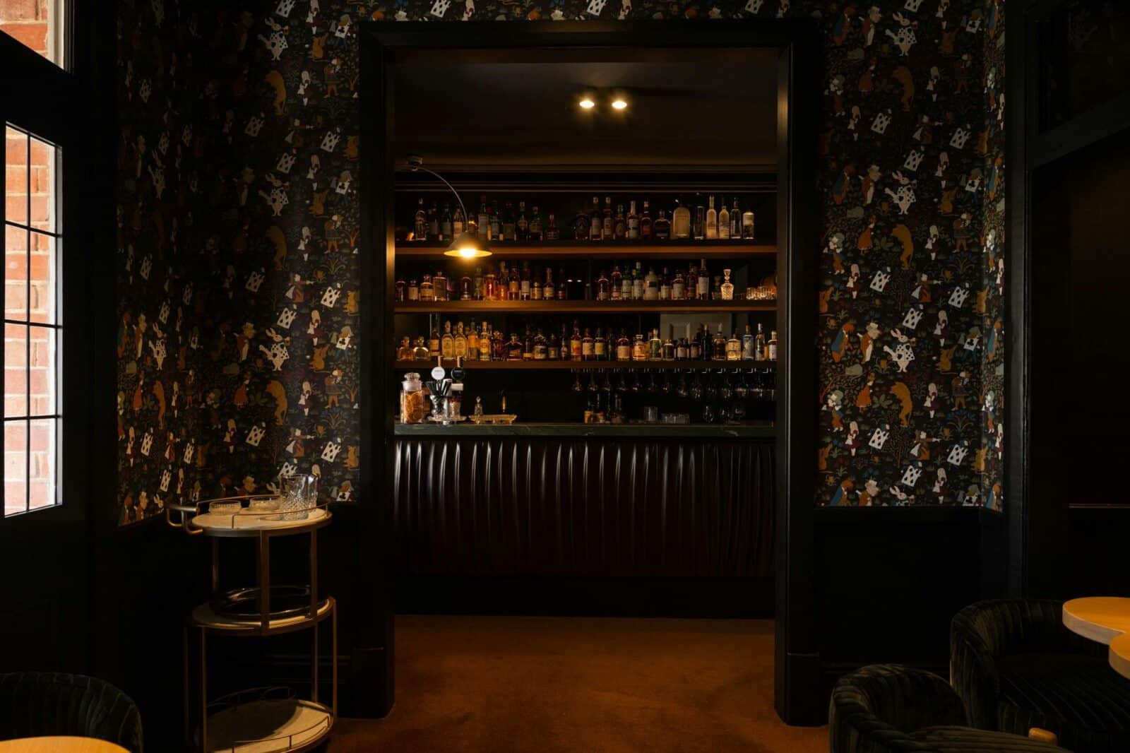 Elegant bar interior featuring a patterned wall and a fully stocked spirits display.