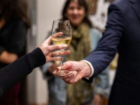 One hand passing a glass of chardonnay to another hand