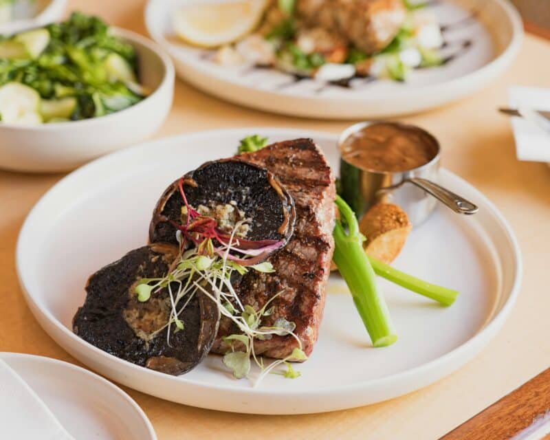 Plate of grilled steak with portobello mushrooms, green vegetables, and sauce at the Criterion.