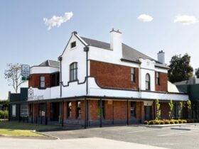 Exterior of the Cross Keys Hotel featuring its red-brick facade, white accents and spacious verandah