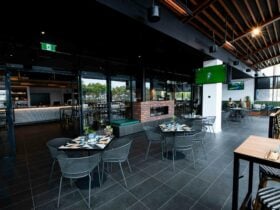 A room with high ceilings and fairy lights is set with tables for lunch