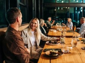 Group Dining at a long table enjoying food and drinks in a modern ocean-to-table restaurant.