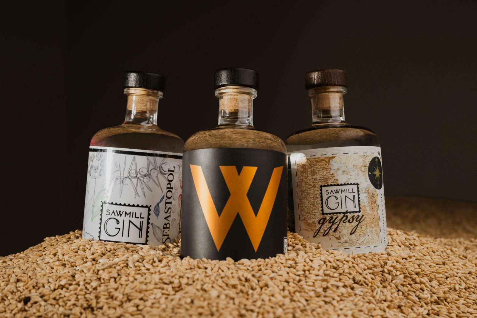 Trio of Sawmill Gin bottles nested on wheat