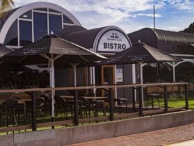 Exterior shot of a pub with an outdoor seating area including black umbrellas and tables.