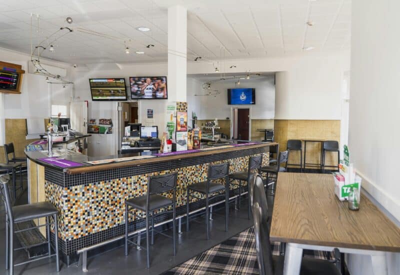 The bar with mosaic tiling at The Bushmanâs Arms, featuring TVs and a variety of seating options
