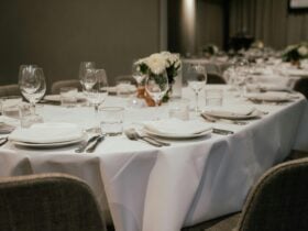 A sophisticated dining table set with wine glasses, silverware, and white floral centerpieces.