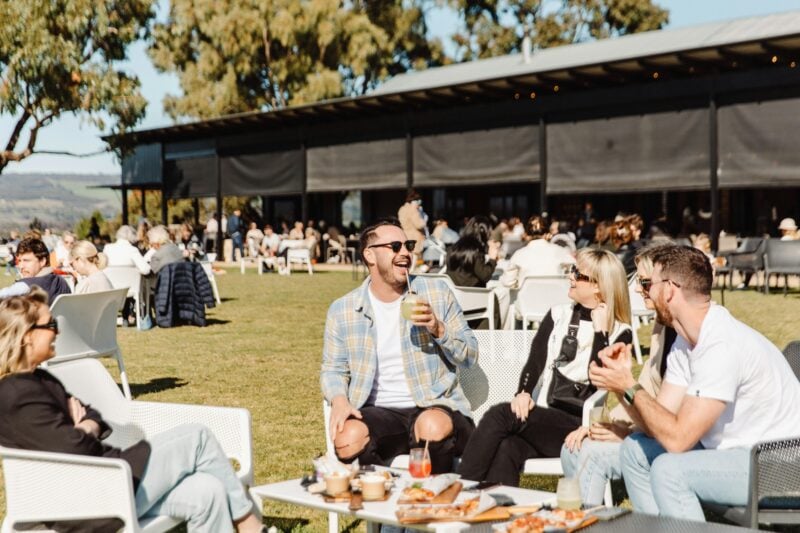 people enjoying drinks and food on table settings outside on the lawn