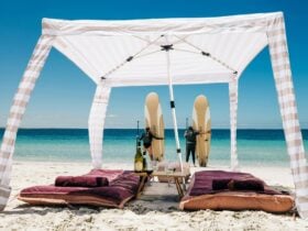 Two people with paddleboards standing in front of beach cabana, Louth Island