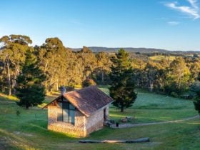 Stone art studio pictured amongst trees and hills