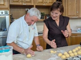 WEA Tutor Andre Guerinet demonstrates rolling a ball of dough to a smiling female student