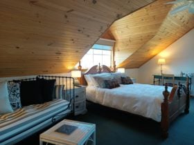 Queen bed in a dormer window with separate seating area, carpeted, in black, white and green colours