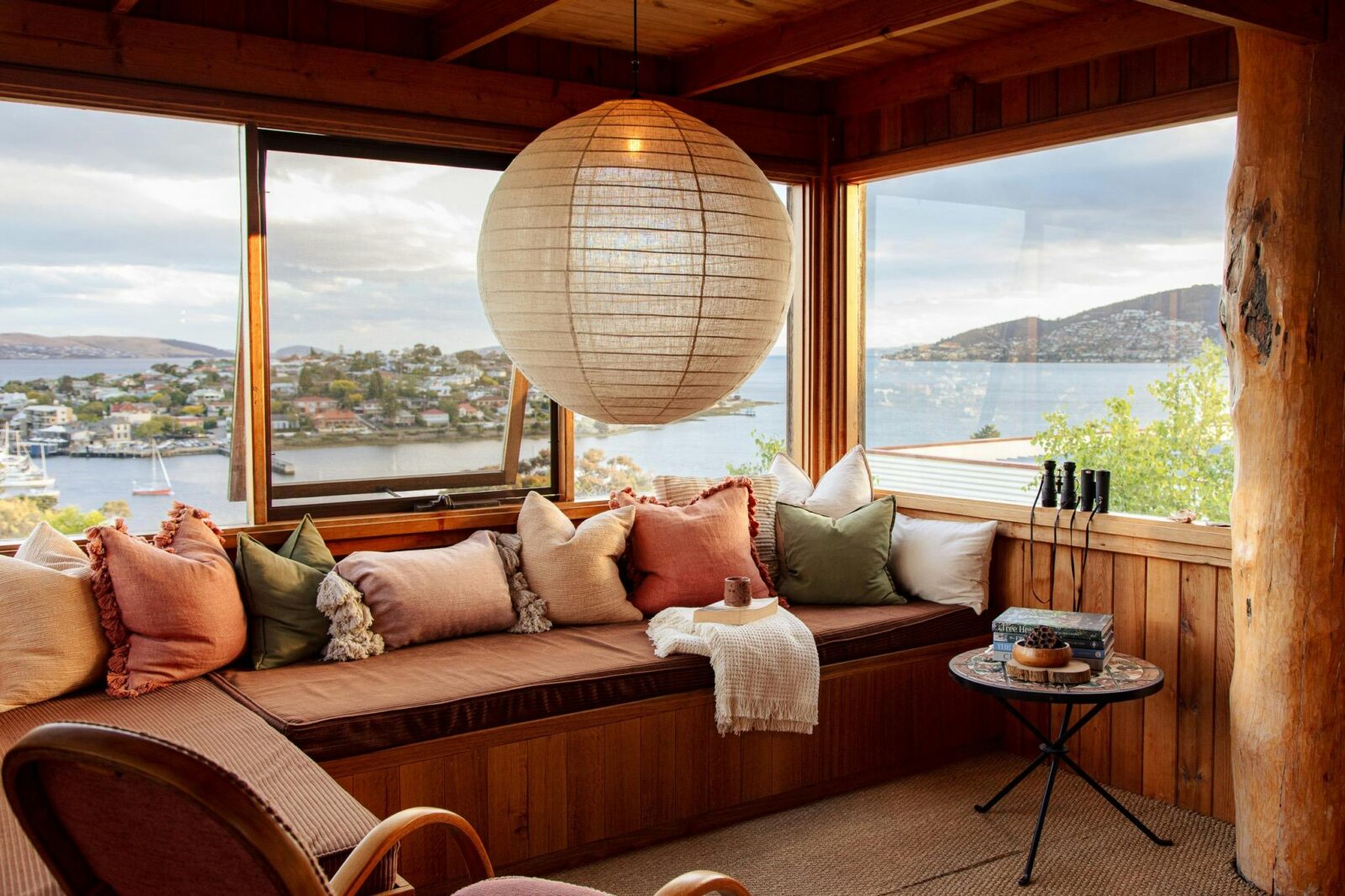 A large daybed, window seat, featuring a linen lantern lightshade.