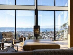 The vast living room, flooded with natural light and framed by floor-to-ceiling windows