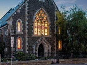 historic bluestone church at dusk, with stained glass windows lit from within