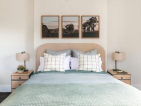 Stylish queen bed, made up with green cover, upholstered bedhead, bedside tables, lamps