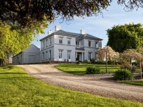 A heritage listed 1830s building in front of a green spring garden.