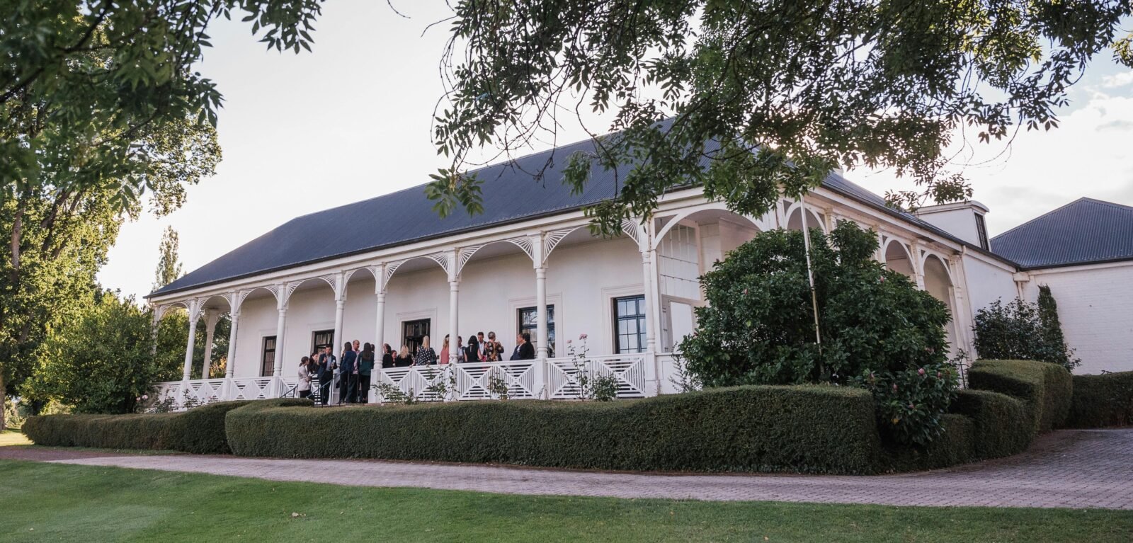 Quamby Homestead, white with elegant arches, behind a box hedge and rose garden