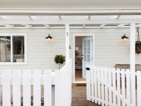 A white beach cottage with picket fence and welcoming open front door.