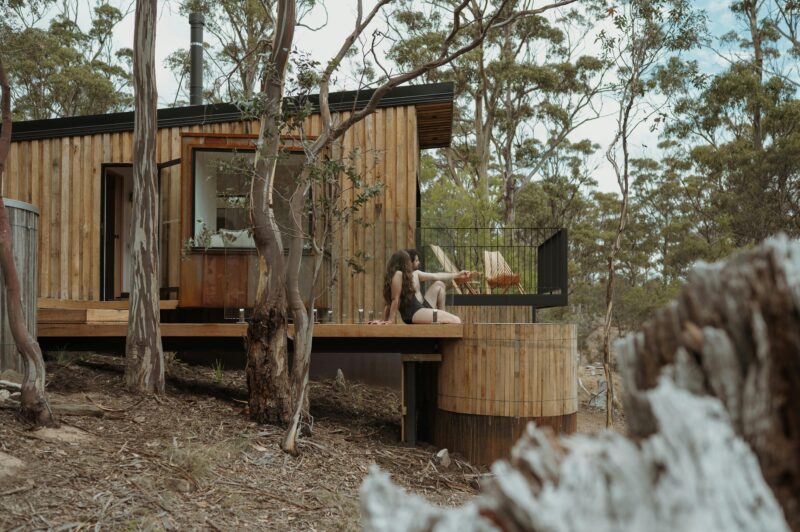 Couple sitting in hottub with cabin and trees in background