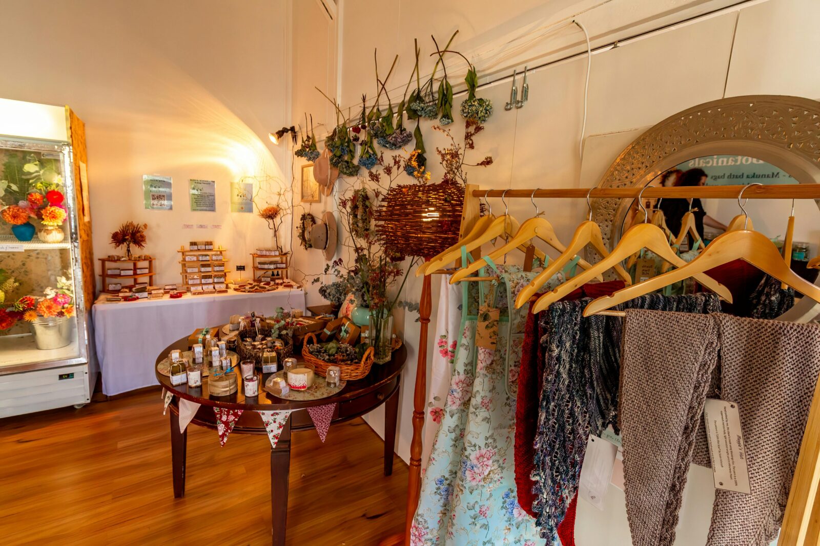 Handknitted shawls scarves hats , dried flowers adorn the walls, and soaps are on display.