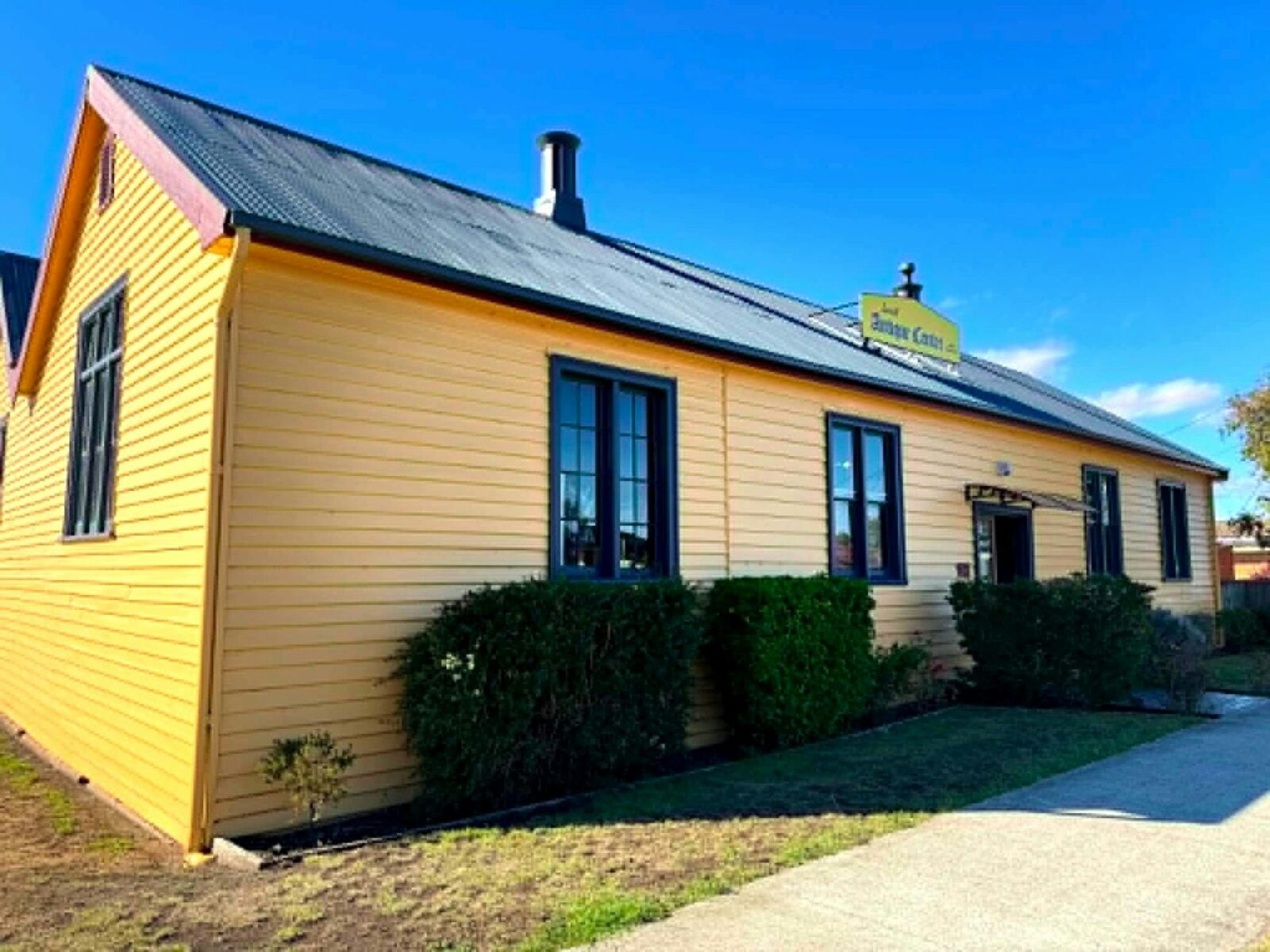 Yellow heritage weatherboard building with Sorell Antique Centre sign on roof