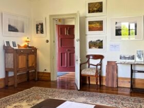 A gallery studio doorway with art and photography on walls of heritage home filled with antique