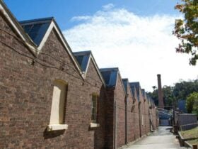 Red brick facade of building with zig zag roof, blue sky and white clouds
