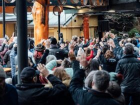 A group of people dancing outdoors in front of a stage