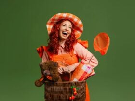 Emma Memma in an orange dress with a picnic basket and a net