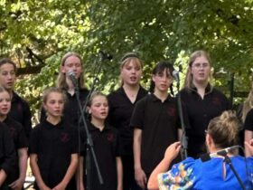 A choir of young people standing outside in front of microphones
