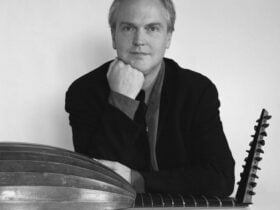 Black and white photo of a man with a lute on his lap